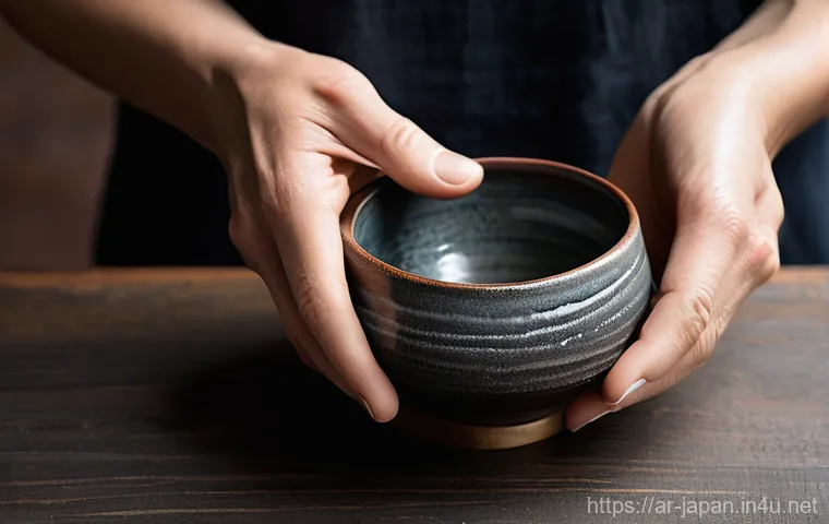 일본 전통 도자기 제작 - **Prompt: Wabi-Sabi Raku Tea Bowl and Artisan's Hands**
    A close-up, high-resolution photograph c...
